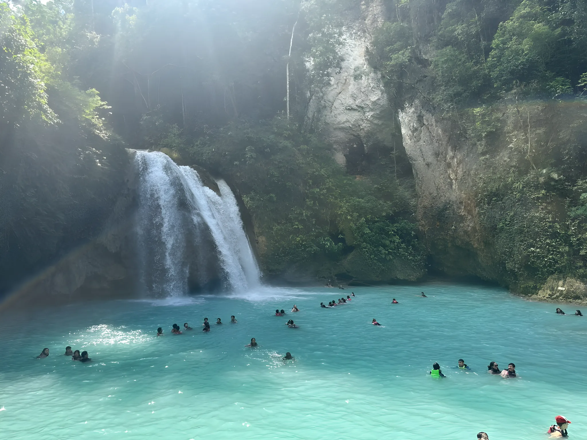 Travellers swimming in the turquoise pool at Kawasan Falls, Cebu